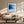 Black-framed blue abstract print above a cream sofa and low wooden coffee table.