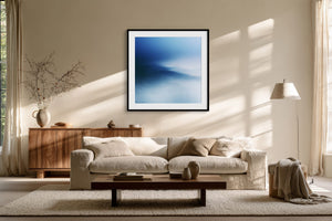 Black-framed blue abstract print above a cream sofa and low wooden coffee table.