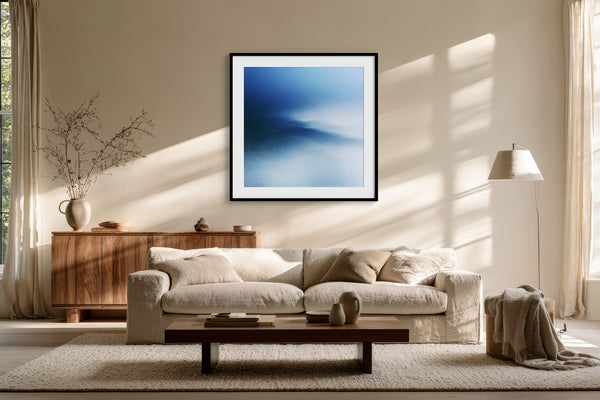 Black-framed blue abstract print above a cream sofa and low wooden coffee table.