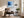 Black-framed blue abstract print above a brown lounge chair, side table, and floor lamp.