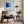 Black-framed blue abstract print above a brown lounge chair, side table, and floor lamp.