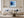 Black-framed blue abstract print above a white sofa with pale blue cushions.