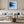 Black-framed blue abstract print above a white sofa with pale blue cushions.