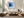 Black-framed blue abstract print above a low cream sectional and wooden coffee table.