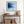 Black-framed blue abstract print above a rustic console table with woven baskets.