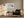 Framed pale blue coastal abstract above a dark armchair, side table, and floor lamp.