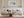 Light wood-framed coastal abstract above a white sofa with pale blue cushions.