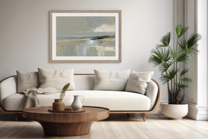Pale Estuary, matted in a light wood frame, displayed above a white sofa and round coffee table.