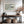 Pale Estuary in a light wood frame above a console table between two staircases.