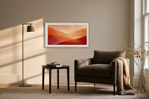 White-framed layered dune artwork above an armchair, side table, and black floor lamp.