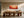 Framed red and peach dune artwork displayed above a long wooden dining table.