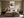 Framed grey and black abstract artwork centered above a bed with neutral bedding.