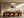 Framed abstract landscape above a long wooden dining table with sculptural chairs.