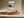Framed grey and charcoal abstract artwork above a low wooden sideboard in sunlight.