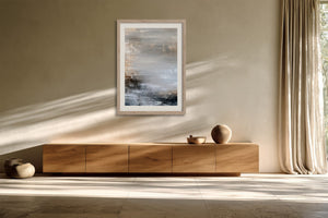 Framed grey, beige, white, and charcoal abstract artwork above a wooden sideboard.