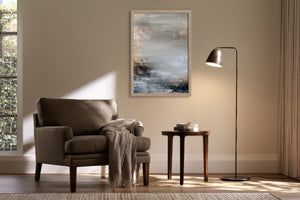 Framed layered abstract artwork above an armchair and side table with a floor lamp.