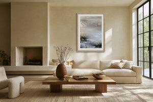 Framed layered abstract artwork above a cream sofa and wooden coffee table.