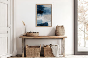 Blue and white abstract artwork above a rustic wooden console with woven baskets and a large window.