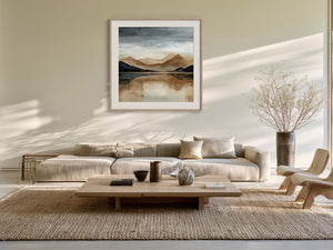 Framed mountain lake artwork above a cream sectional sofa and low wood coffee table.