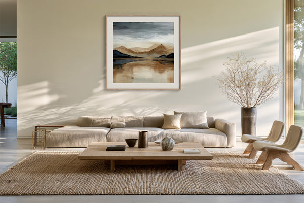 Framed mountain lake artwork above a cream sectional sofa and low wood coffee table.