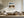 Framed mountain lake artwork displayed above a white sectional sofa and wood coffee table.