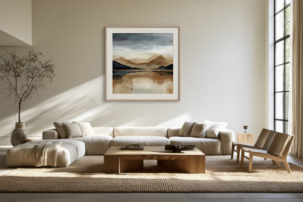 Framed mountain lake artwork displayed above a white sectional sofa and wood coffee table.