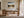 Mountain lake artwork above a wood desk with chair, shelving, and floor-to-ceiling windows.