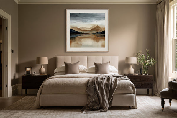 White-framed mountain lake artwork centered above a bed between dark wood nightstands.