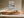 Framed blue-grey seascape above a long wooden sideboard with ceramic objects.