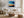 Black-framed abstract sunset print above a white sofa with pillows and a round wood coffee table.