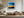 Black-framed abstract sunset print above a cream sectional sofa and low wood coffee table.