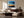 Black-framed abstract sunset print above a dark wood sideboard behind cream seating.