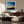 Black-framed abstract sunset print above a dark wood sideboard behind cream seating.