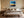 Black-framed abstract sunset print centered above a bed with layered neutral bedding.
