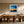 Black-framed abstract sunset print above a long wooden dining table with sculptural chairs.