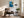 Framed blue glacial river artwork above an armchair, side table, floor lamp, and plant.