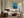 Framed blue glacial river artwork above a fireplace and low seating near tall windows.