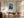 Framed blue glacial river artwork above a wooden desk and upholstered office chair.
