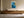 Framed blue glacial river artwork centered above a long wooden sideboard with ceramic vessels.