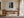 Light-framed aerial shoreline artwork with a red rowing boat above a wooden desk.