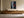 Light-framed shoreline artwork with a red boat mounted above a long wooden sideboard.