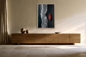 Light-framed shoreline artwork with a red boat mounted above a long wooden sideboard.
