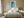 Framed turquoise shoreline artwork above a neatly made bed between wooden nightstands.