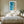 Framed turquoise shoreline artwork above a neatly made bed between wooden nightstands.