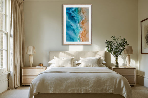 Framed turquoise shoreline artwork above a neatly made bed between wooden nightstands.