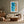 Framed turquoise shoreline artwork above a cream sofa, wooden coffee table, and leather lounge chair.