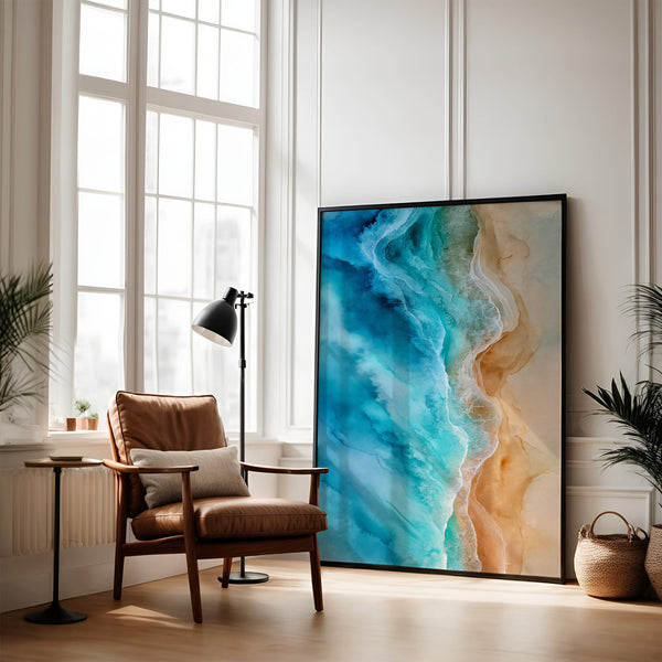 Large black-framed turquoise ocean-and-sand artwork leaning beside a leather armchair and floor lamp.