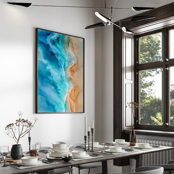 Large black-framed ocean-and-sand artwork above a set dining table near tall windows.