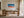 Framed aerial wave artwork displayed above a wooden desk in a sunlit workspace.
