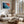 Ember Tide print in a light wood frame above a cream sectional beside tall windows.